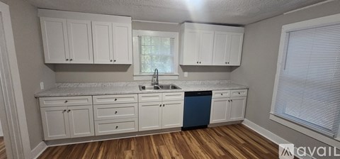 A kitchen with white cabinets and a blue trash can.