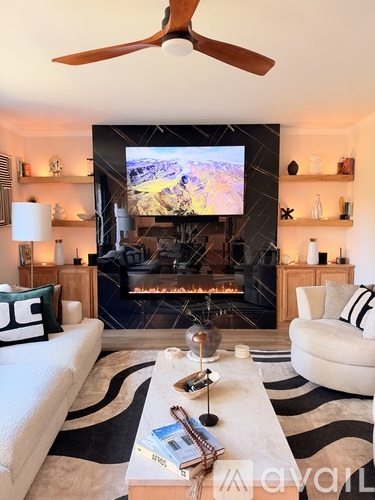 A living room with a fireplace and a television mounted above it.