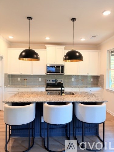 A kitchen with a granite countertop and white bar stools.