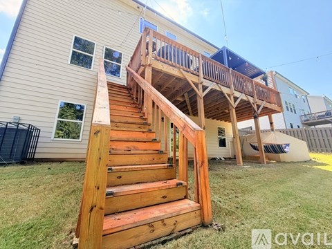 A wooden staircase with a balcony overlooks a grassy area.