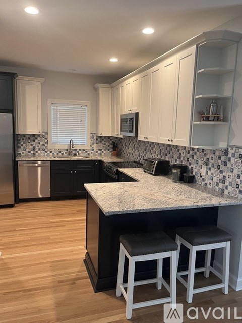 A kitchen with white cabinets and a black countertop.
