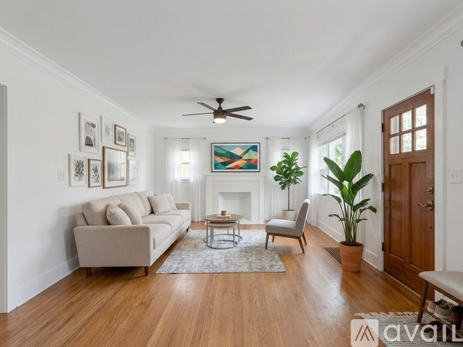 A living room with a beige couch, a coffee table, a ceiling fan, and a painting on the wall.