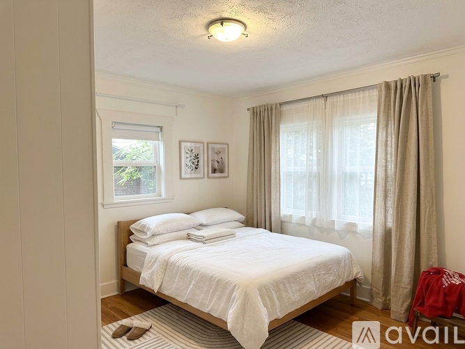 A bedroom with a neatly made bed and a window with curtains.