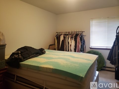 A bed with a green and blue comforter is in a bedroom with a closet and window.