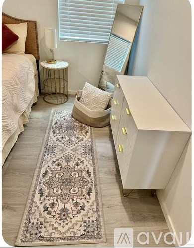 A bedroom with a large rug in the middle of the room.