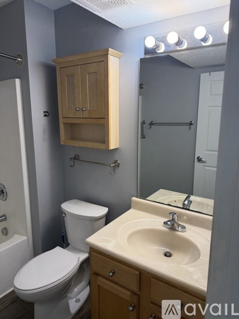 A bathroom with a toilet, sink, and cabinet.