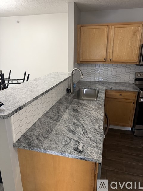 A kitchen with a granite counter top and wooden cabinets.