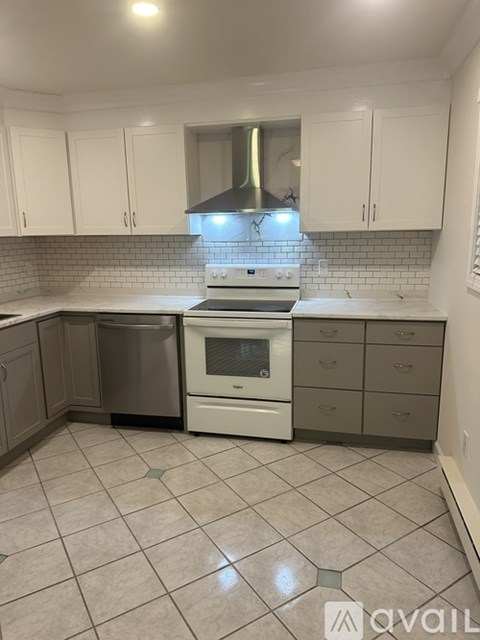 A kitchen with white cabinets and a white stove top oven.