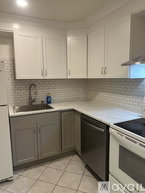 A kitchen with white cabinets and a black dishwasher.
