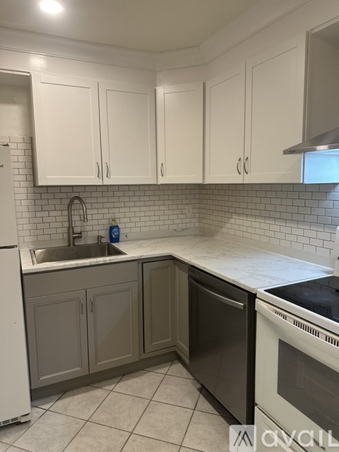 A kitchen with white cabinets and a black dishwasher.