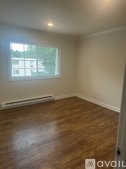 A room with wooden flooring and a window with blinds.