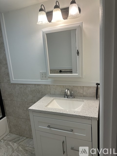 A bathroom with a sink, mirror, and light fixture.