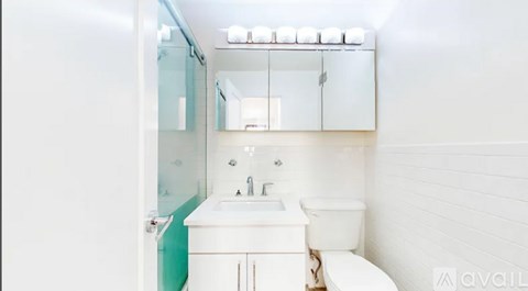 A white bathroom with a toilet, sink, and mirror.