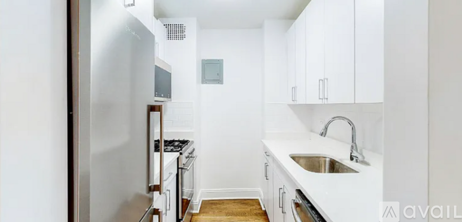 A kitchen with white cabinets and a stainless steel refrigerator.