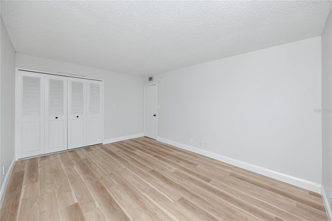 A room with white walls and wooden flooring with a white door.