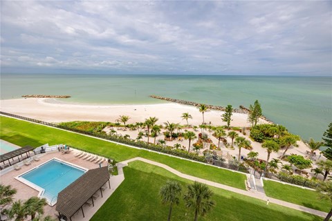 A beautiful beachfront property with a swimming pool and palm trees.