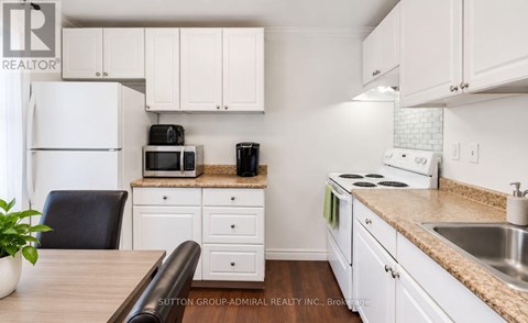 A kitchen with white cabinets and appliances.