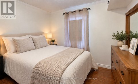 A bedroom with a bed, nightstand, and a mirror.