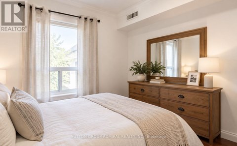 A bedroom with a bed, dresser, and window.