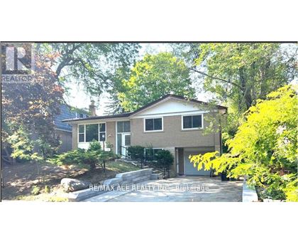 A house with a brown roof and a white door is surrounded by green trees.