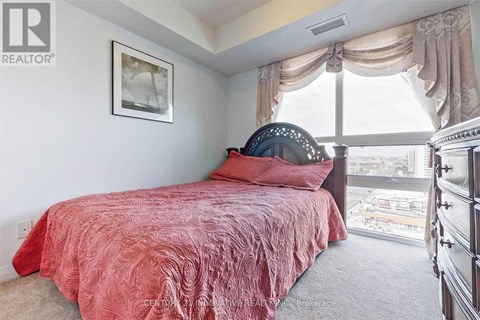 A bedroom with a red bedspread and a large window.