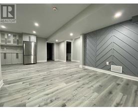 A spacious room with wooden flooring and grey chevron patterned walls.
