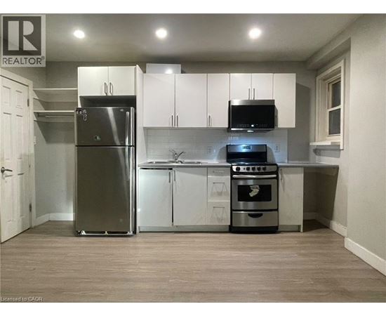 A kitchen with a refrigerator, oven, and microwave.