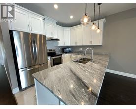 A kitchen with a granite countertop and stainless steel appliances.