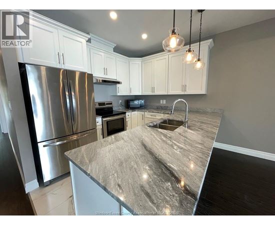 A kitchen with a granite countertop and stainless steel appliances.