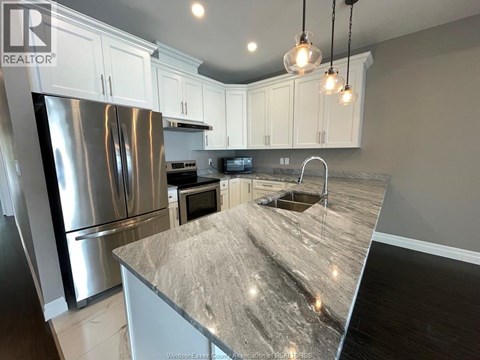 A kitchen with a granite countertop and stainless steel appliances.