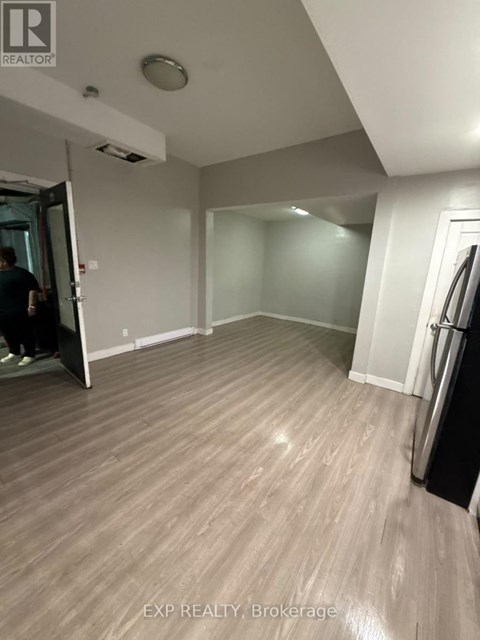 A man is walking into a room with wooden flooring and white walls.