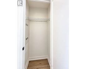A white closet with a shelf and a wooden floor.