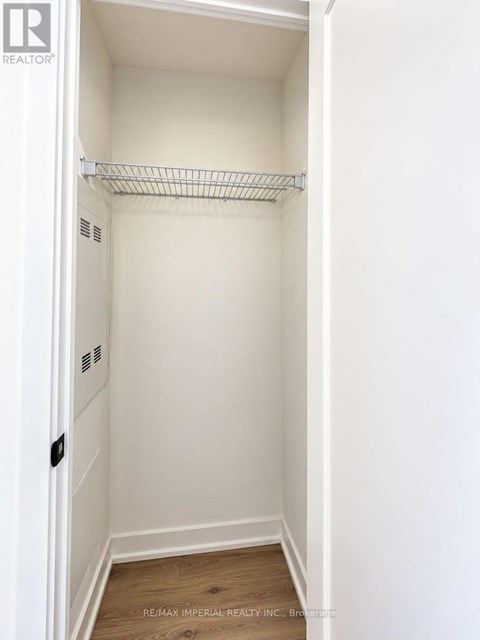 A white closet with a shelf and a wooden floor.