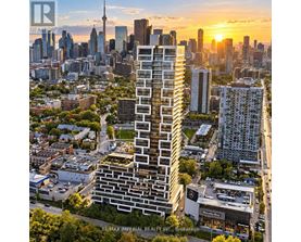 A tall, modern building stands in the foreground of a cityscape at sunset.