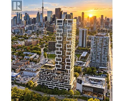 A tall, modern building stands in the foreground of a cityscape at sunset.