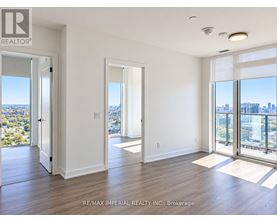 A spacious room with a view of the cityscape through large windows.