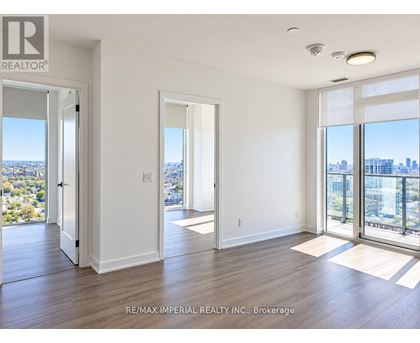 A spacious room with a view of the cityscape through large windows.