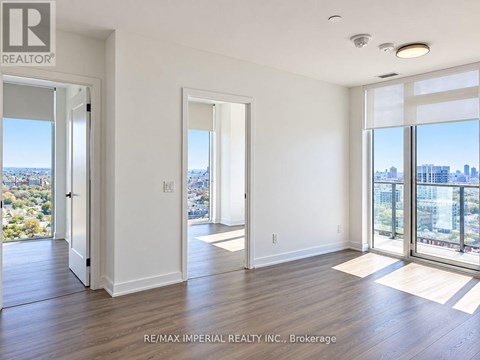 A spacious room with a view of the cityscape through large windows.