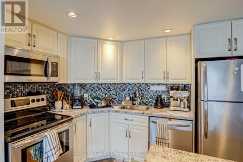 A kitchen with white cabinets and a stainless steel refrigerator.
