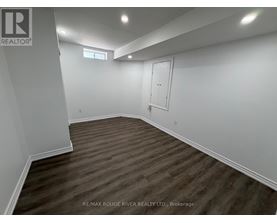 A room with wooden flooring and white walls, with a door and a window.
