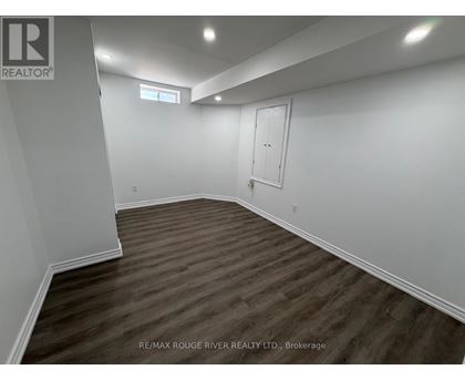 A room with wooden flooring and white walls, with a door and a window.