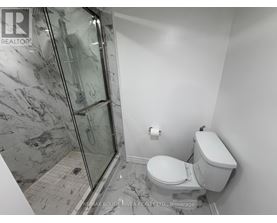 A bathroom with a toilet, a walk-in shower, and a marble floor.