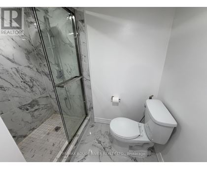 A bathroom with a toilet, a walk-in shower, and a marble floor.