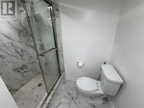 A bathroom with a toilet, a walk-in shower, and a marble floor.