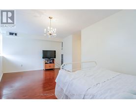 A bedroom with a bed, a television, and a chandelier.