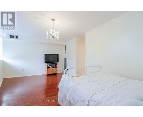 A bedroom with a bed, a television, and a chandelier.