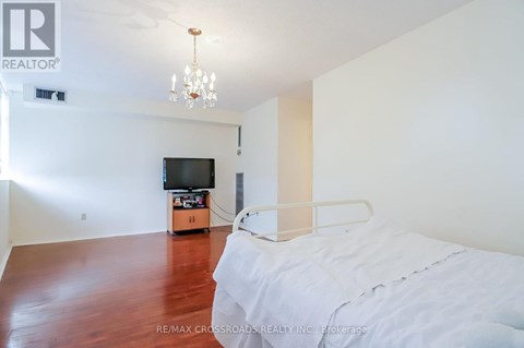 A bedroom with a bed, a television, and a chandelier.