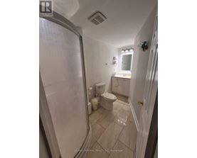 A white bathroom with a toilet, sink, and shower.