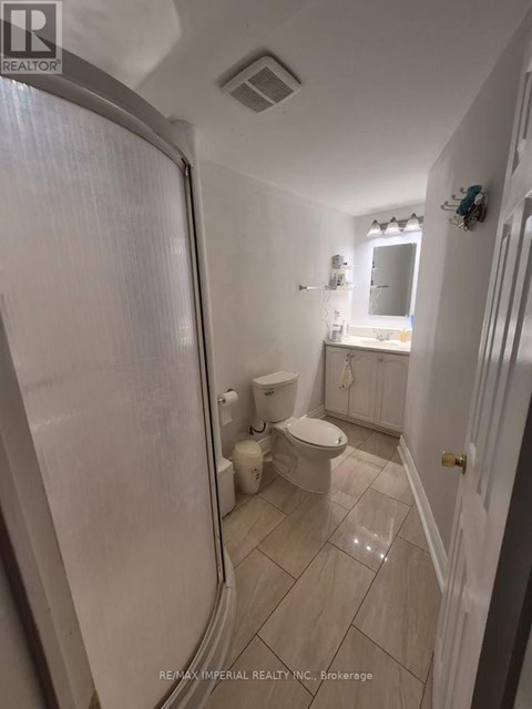 A white bathroom with a toilet, sink, and shower.