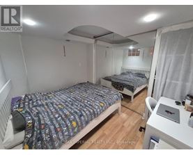 A bedroom with two beds and a desk with a laptop on it.